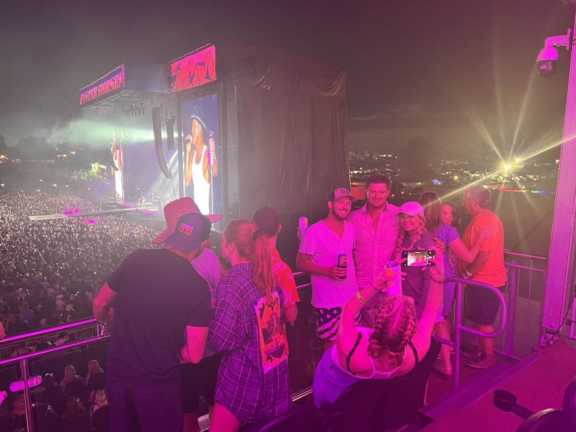 A group of people are standing in front of a stage at a concert.