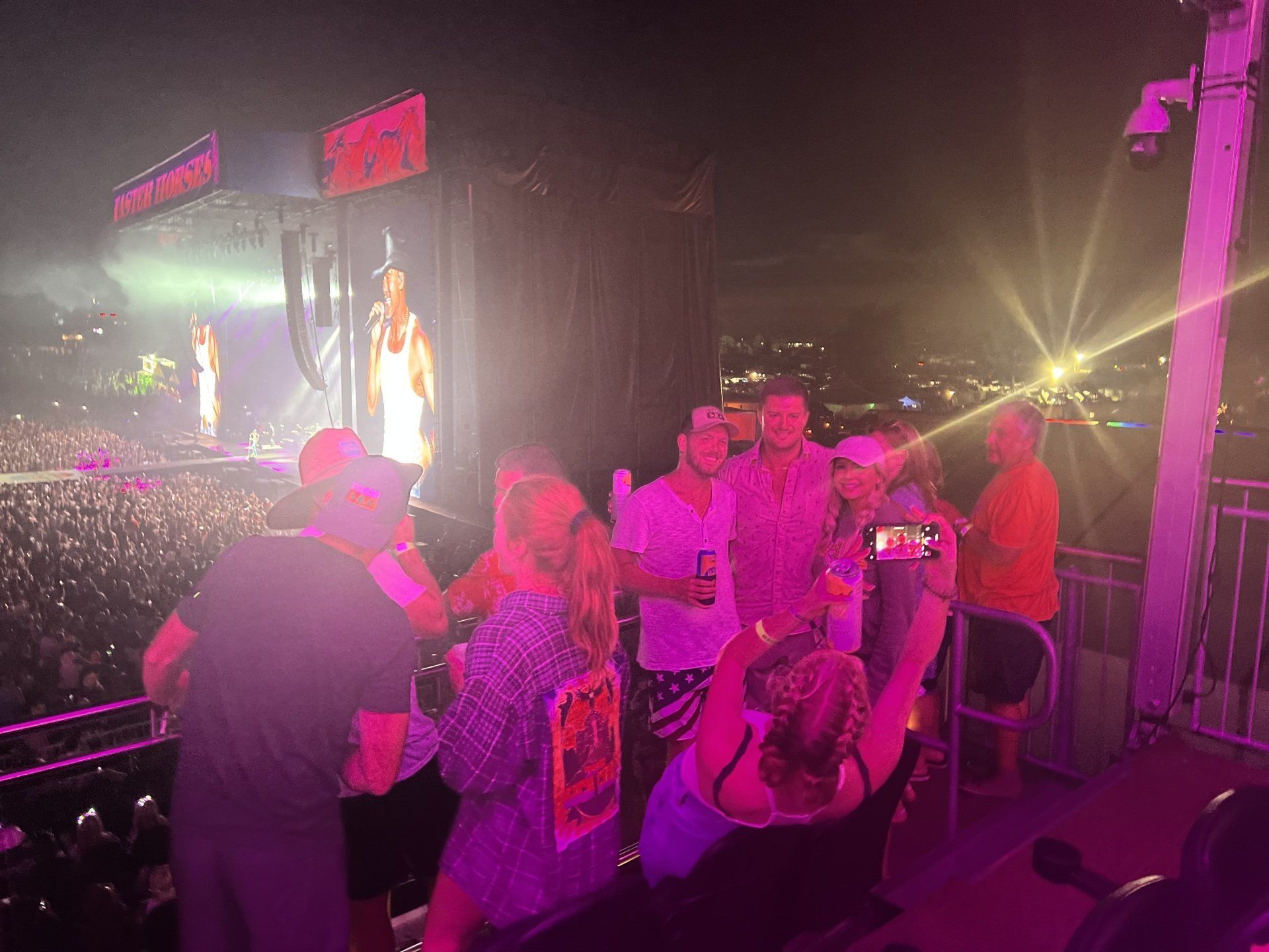 A group of people are standing in front of a stage at a concert.