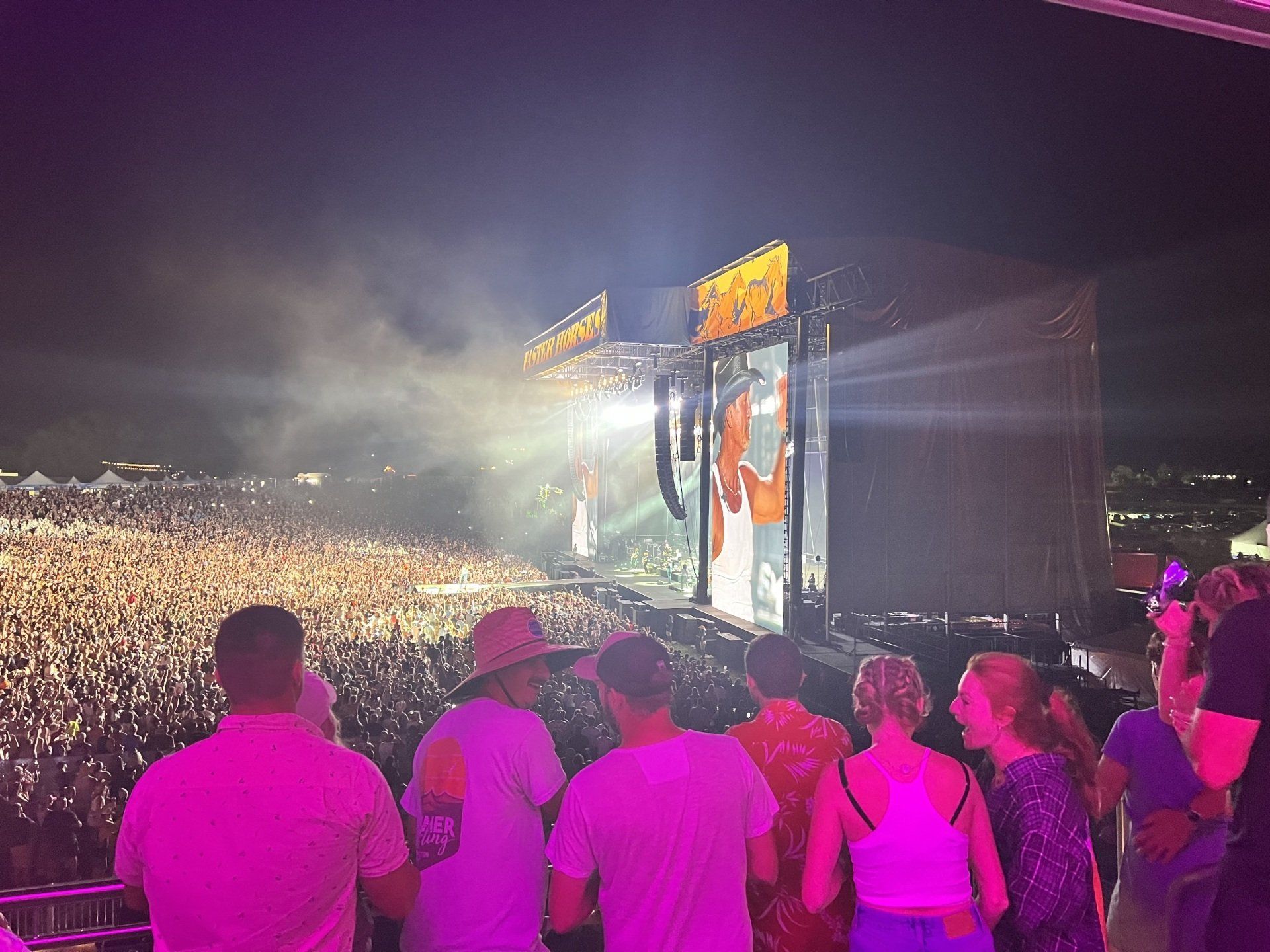 A crowd of people are standing in front of a stage at a concert.