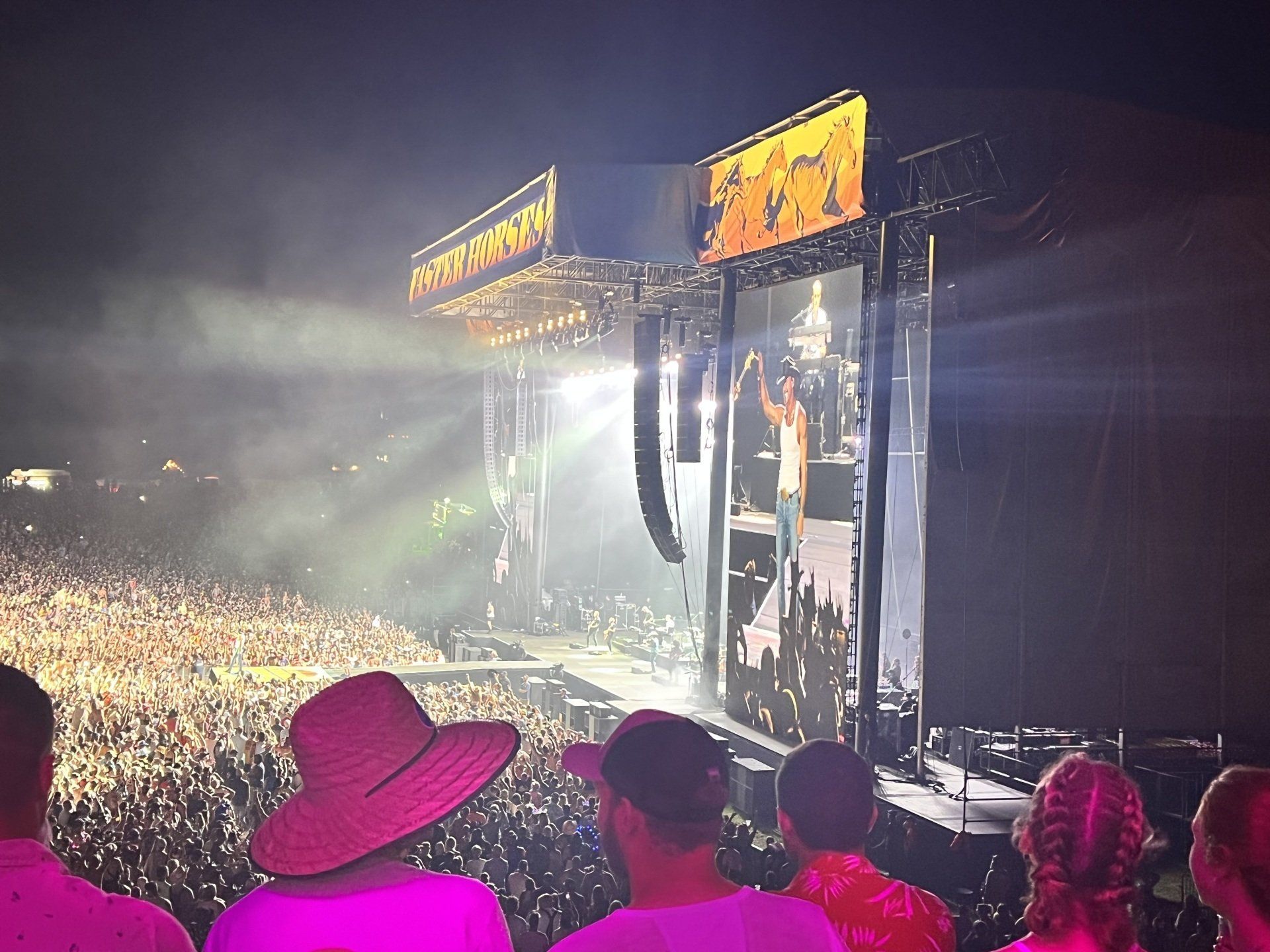 A crowd of people watching a concert with a sign that says first aid kit