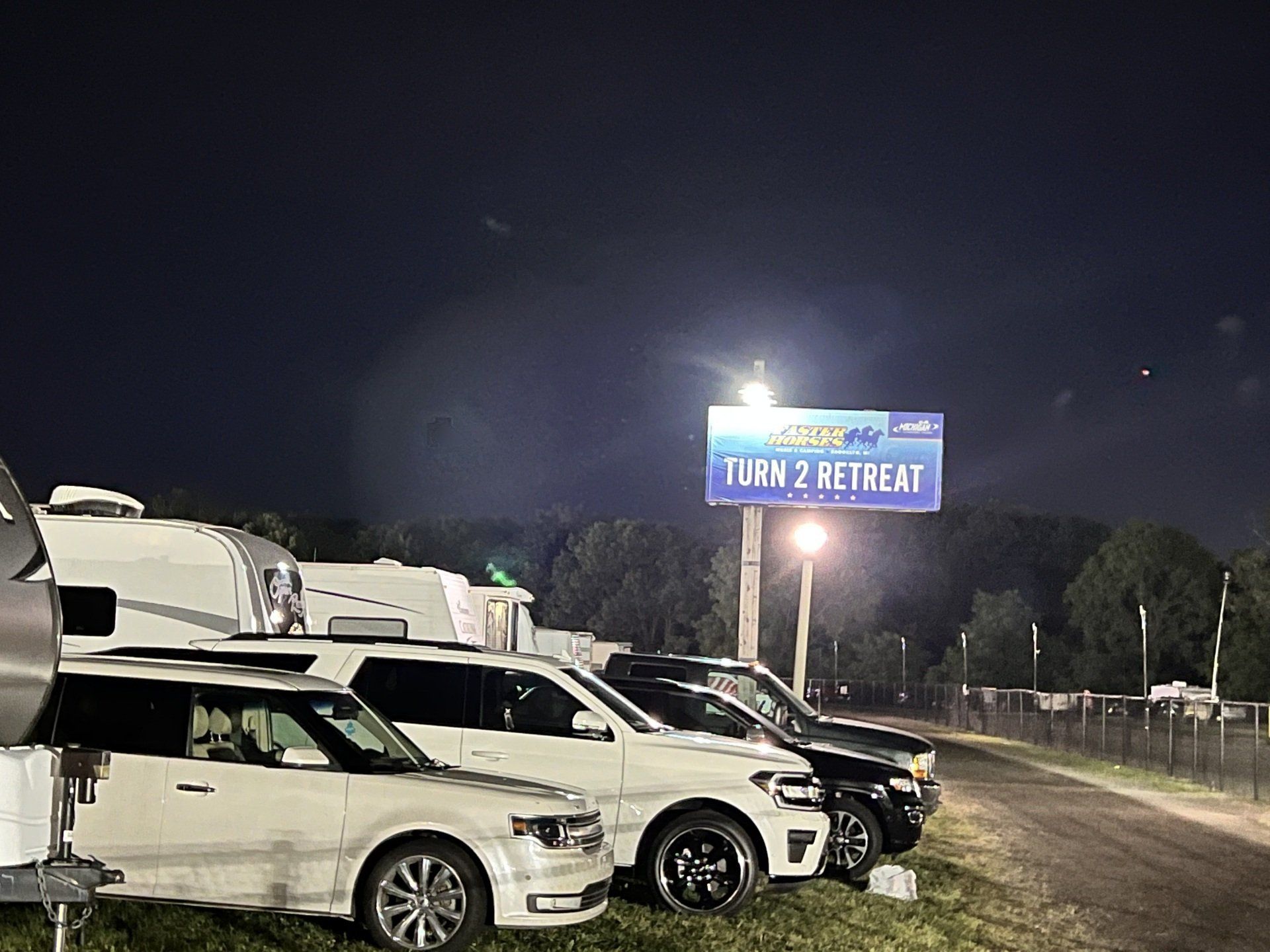 A row of cars are parked in front of a sign that says turn 2 retreat.