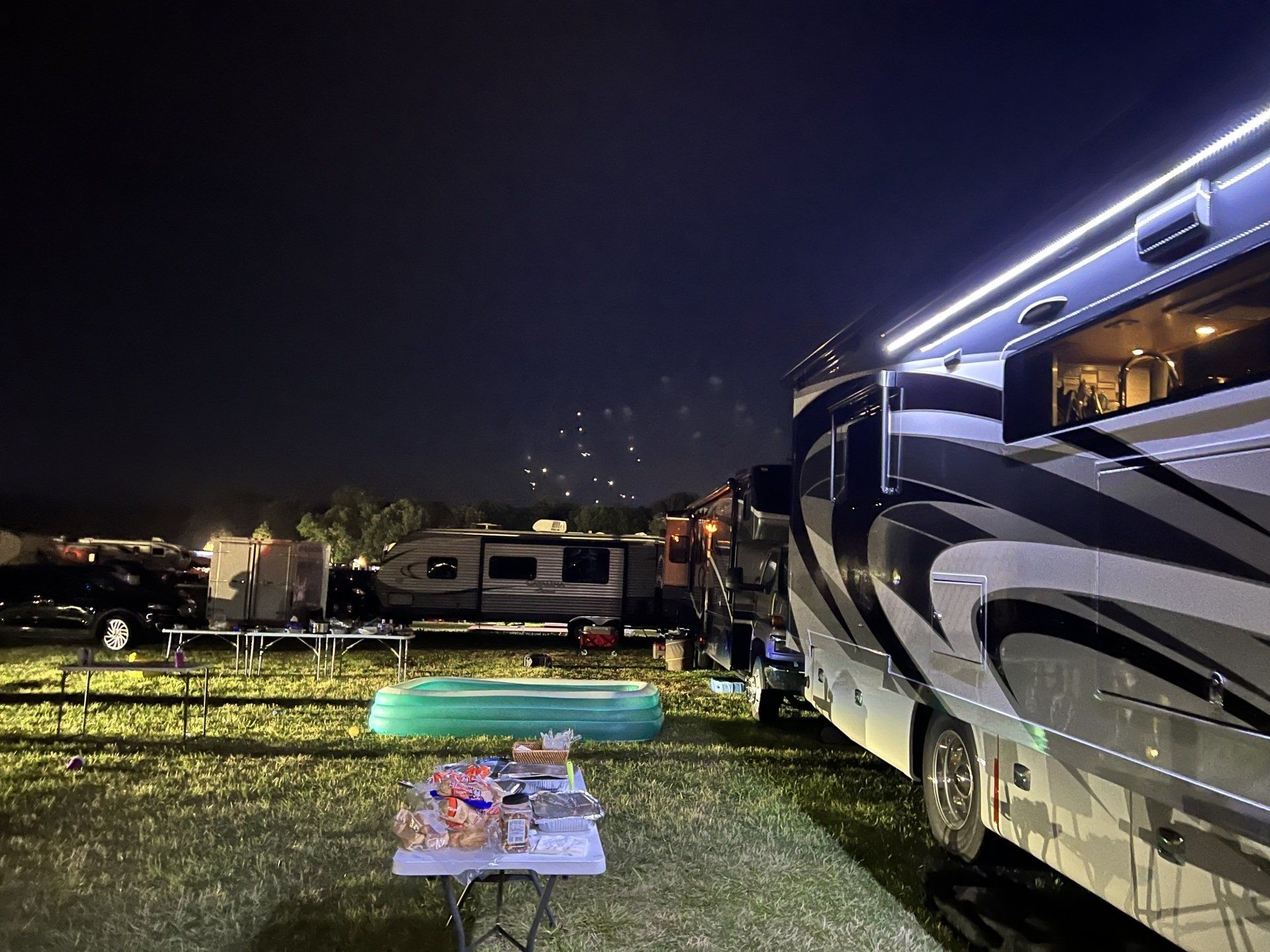 A rv is parked in a campground at night.