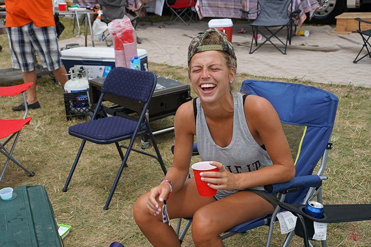A woman is sitting in a chair holding a red cup and laughing.