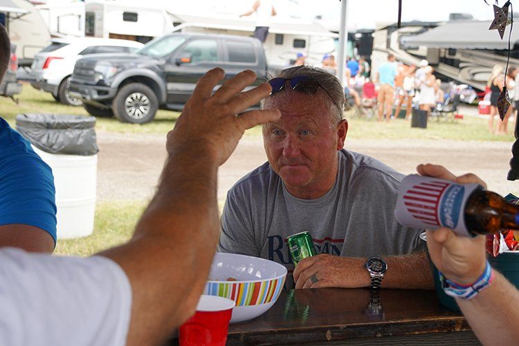 A man is sitting at a table with a bottle of beer and a cup.