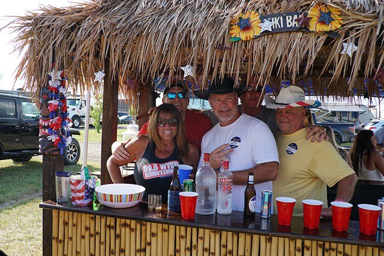 A group of people standing behind a tiki bar.