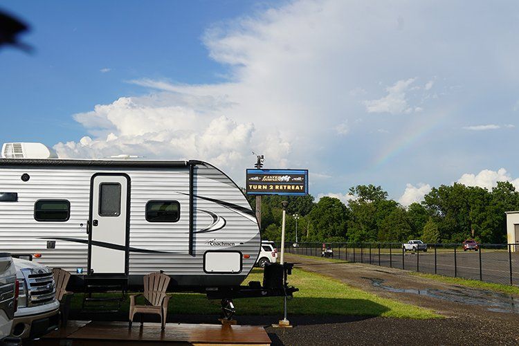 A silver and white rv is parked in a parking lot.
