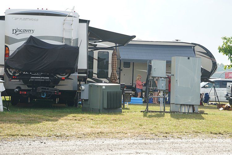A man is standing in front of a rv parked in a field.