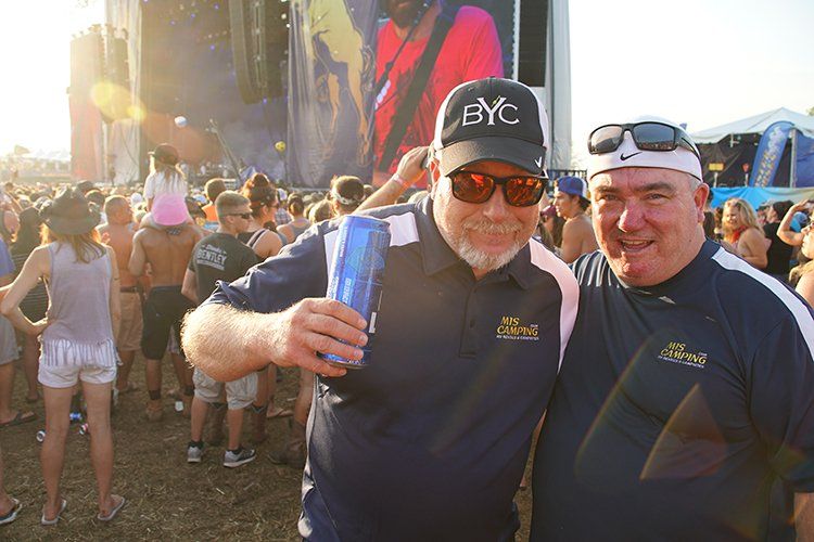 Two men are posing for a picture in front of a crowd at a concert.