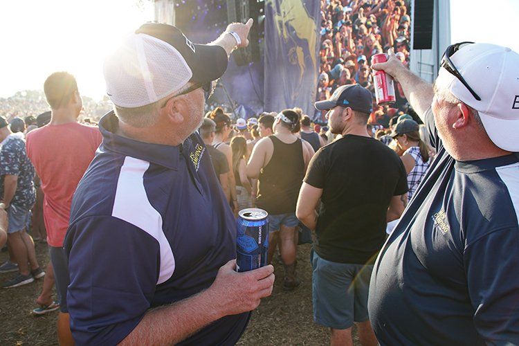 Two men are standing in front of a crowd of people at a concert.