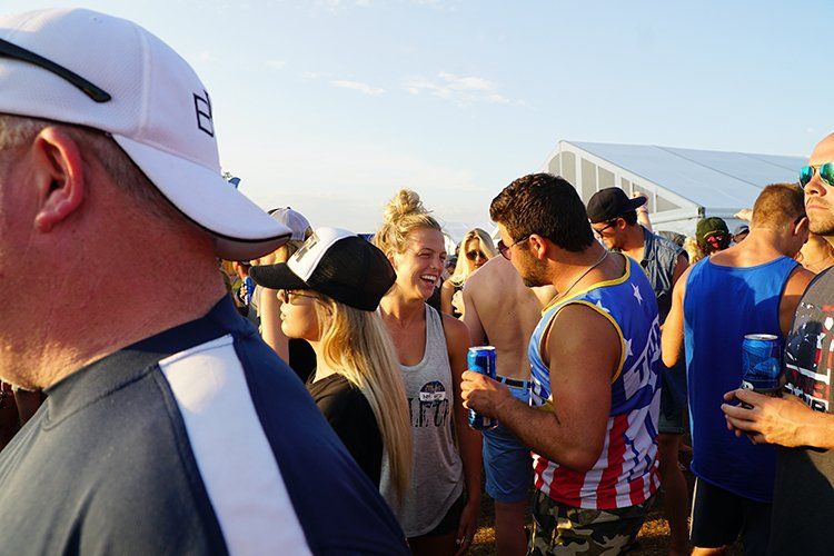 A man in a white hat is standing in a crowd of people.