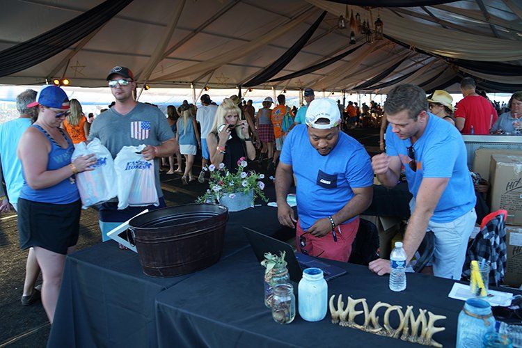 A group of people are standing around a table under a tent.