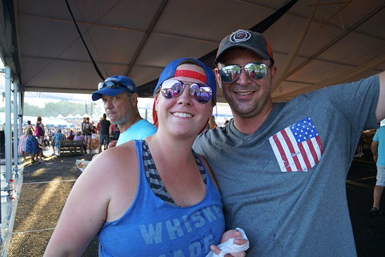 A man and a woman are posing for a picture under a tent.