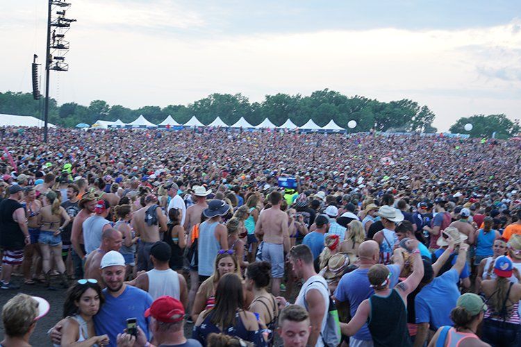 A large crowd of people are gathered at a music festival.