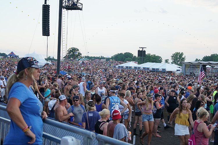 A woman is standing in front of a crowd of people at a concert.