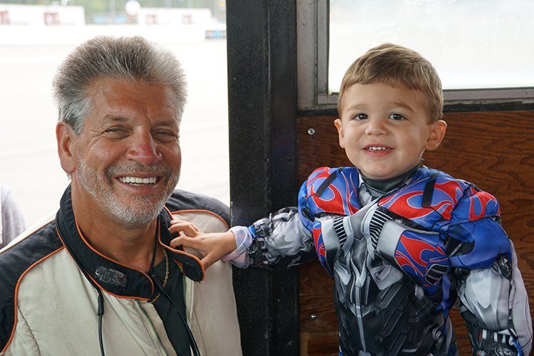 A man and a little boy are posing for a picture . the little boy is wearing a spiderman costume.