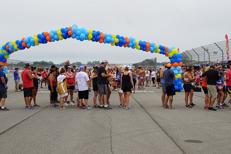 A group of people are standing under a large arch of balloons.