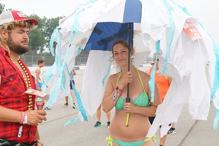 A woman in a bikini is holding an umbrella made out of toilet paper.