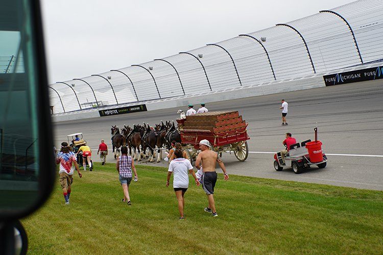 A group of people are running towards a horse drawn carriage on a race track.