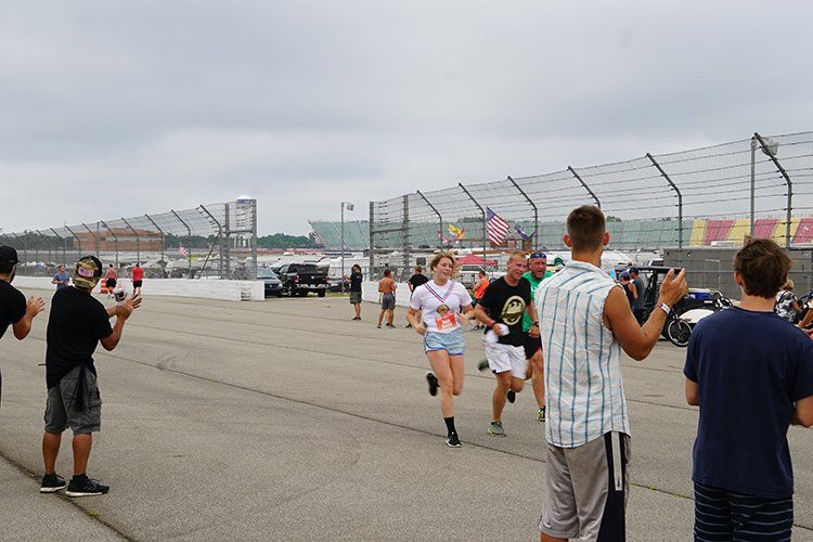 A group of people are standing on a race track taking pictures.