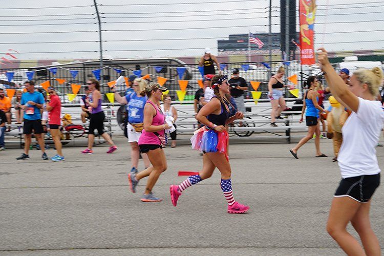 A woman is taking a picture of a group of people running in a race.