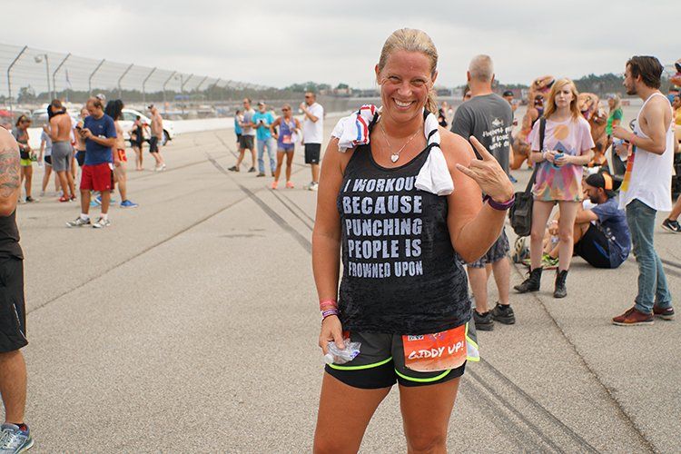 A woman wearing a tank top that says `` because forcing people is impossible '' is standing in front of a crowd.