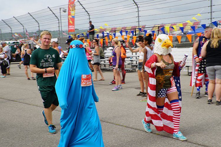 A woman in an american flag costume is walking with a man in a green shirt.