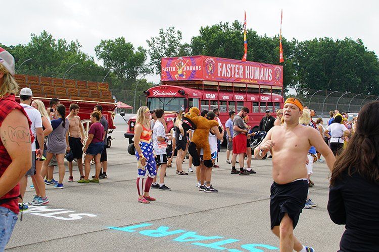 A group of people are gathered in a parking lot with a sign that says faster humans