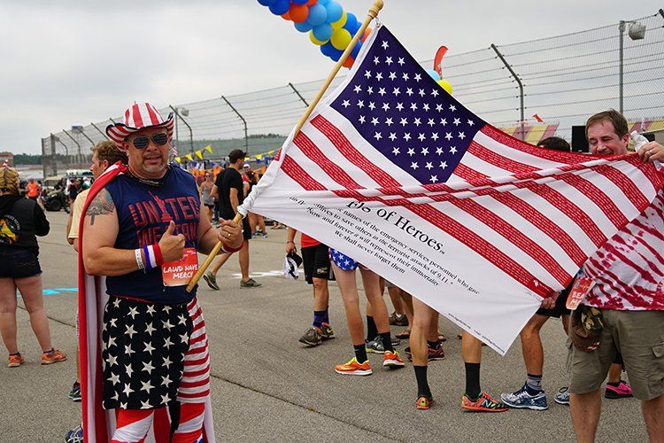 A man in an american flag outfit is holding an american flag.