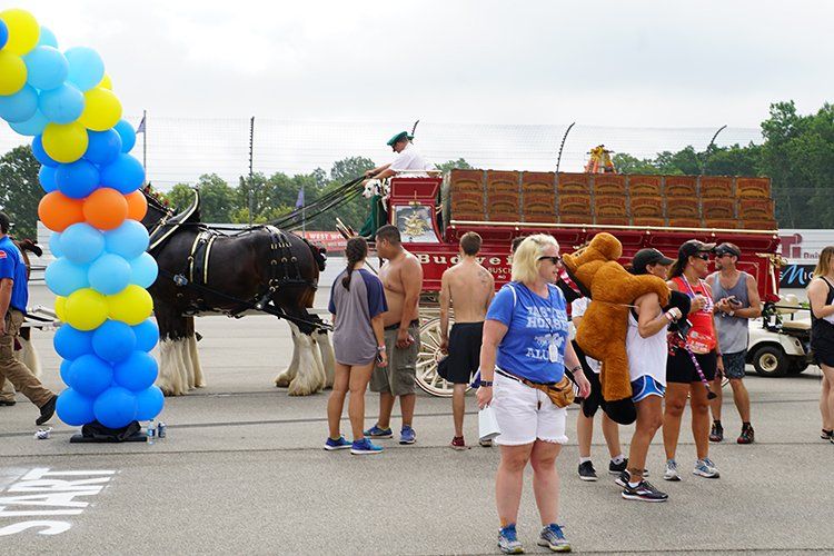 A group of people are standing in front of a horse drawn carriage.