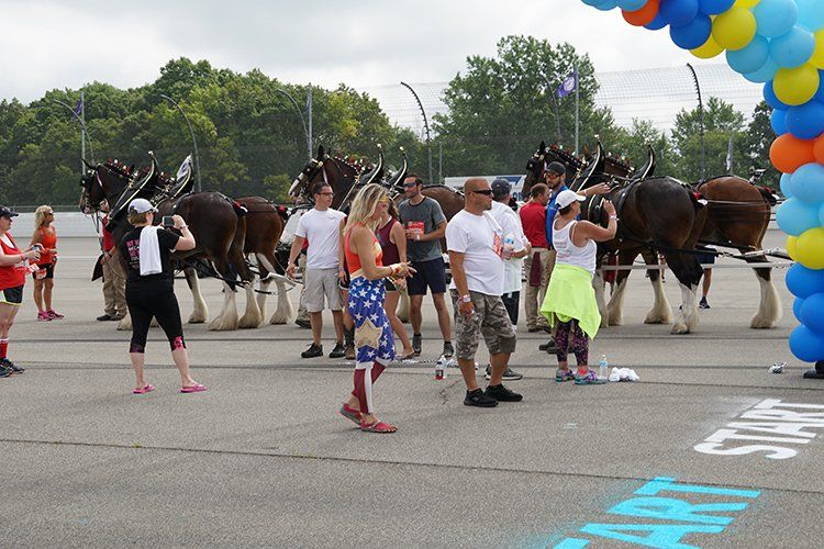 A group of people are standing in front of a horse drawn carriage.