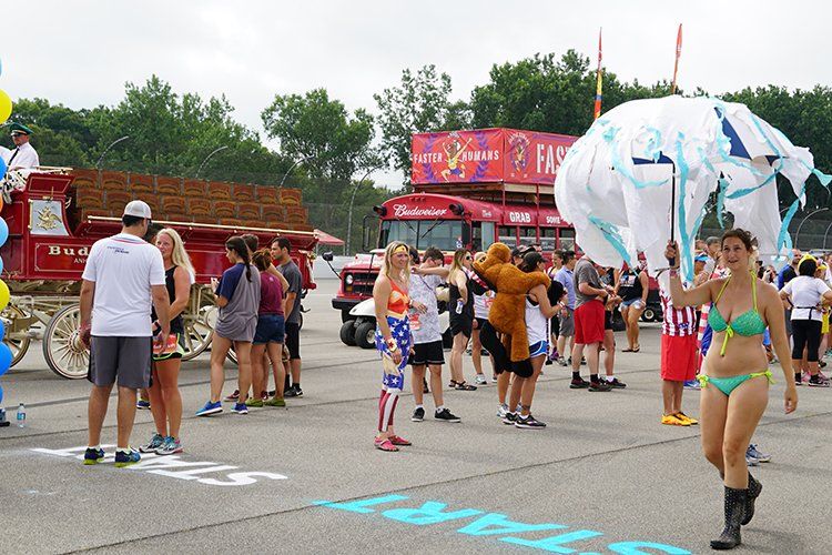 A woman in a bikini is holding a parachute in front of a crowd of people.