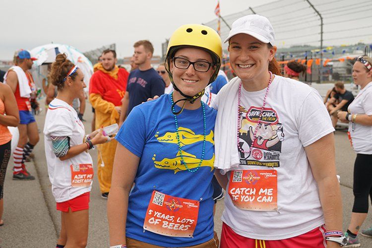 Two women are posing for a picture and one of them is wearing a yellow helmet.