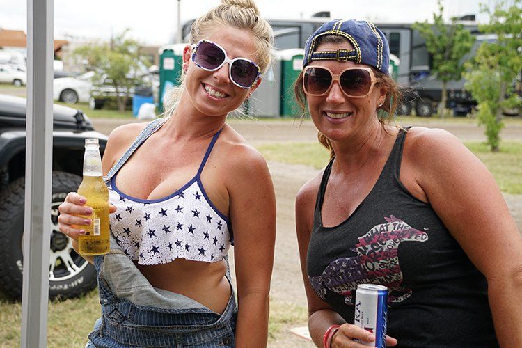 Two women are standing next to each other holding beer bottles.