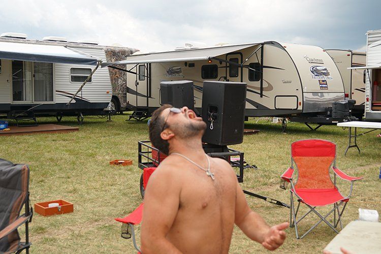 A shirtless man is standing in front of a trailer that says rv on it