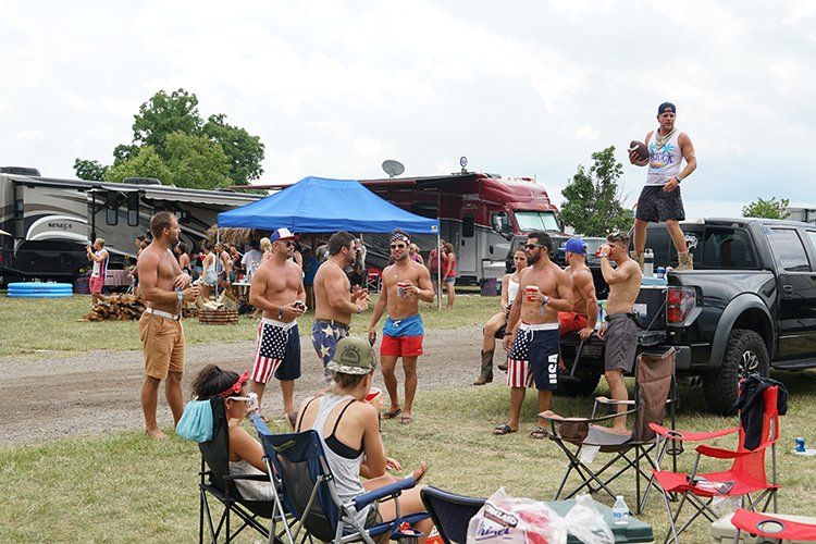 A group of people are standing around a truck in a field.