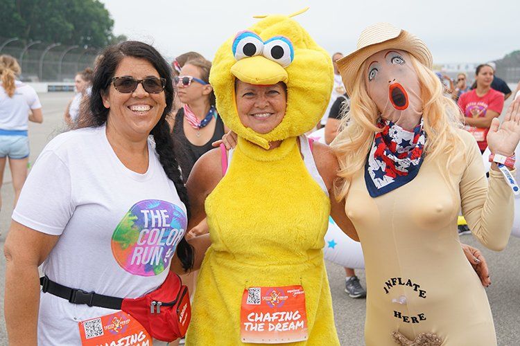 Three women are posing for a picture in sesame street costumes.