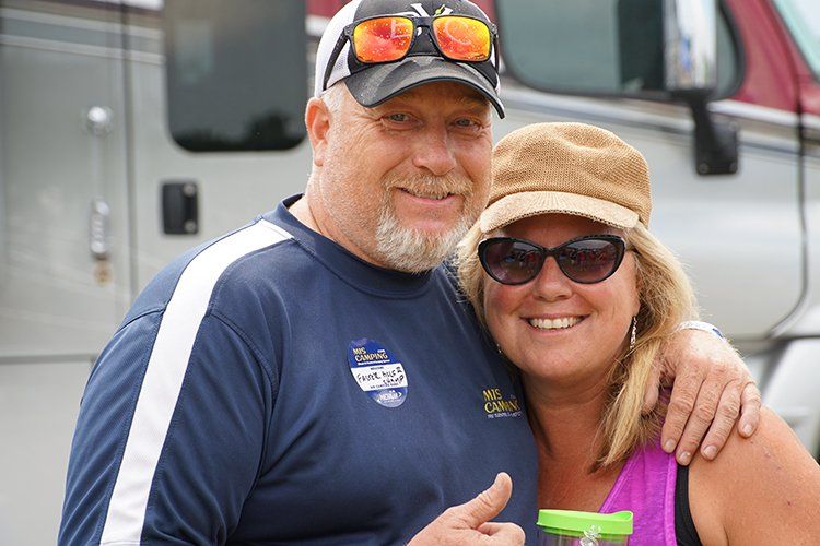 A man and a woman are posing for a picture in front of a truck.