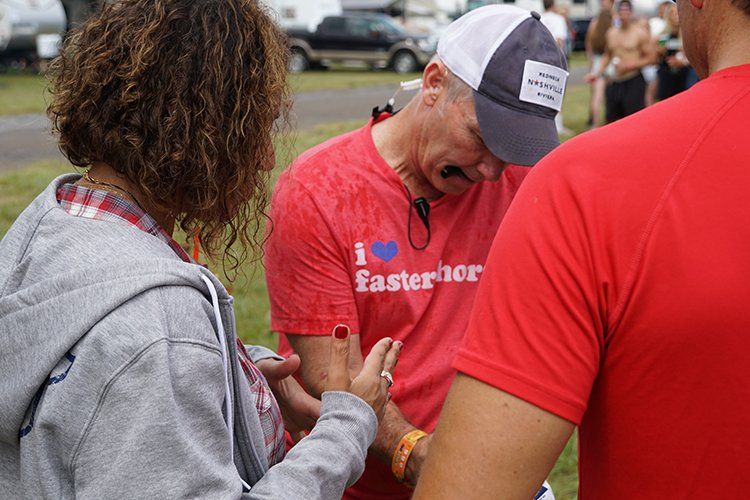 A man wearing a red shirt that says i love faster is talking to a woman.