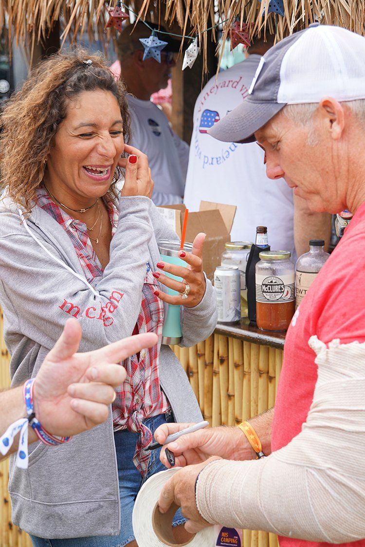 A man and a woman are talking to each other in front of a thatched roof.