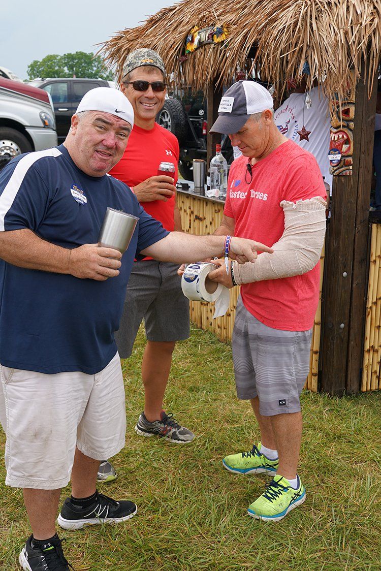 A group of men are standing in a field talking to each other.