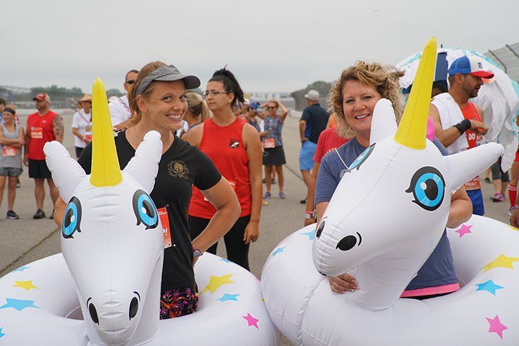 A group of people are standing next to inflatable unicorns.