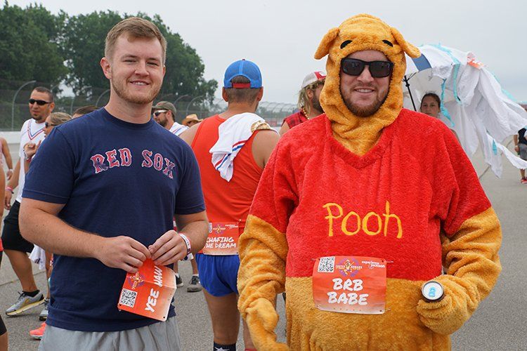 A man in a winnie the pooh costume is standing next to another man