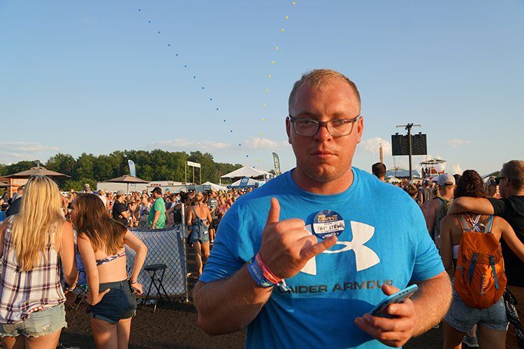 A man wearing a blue under armour shirt stands in front of a crowd