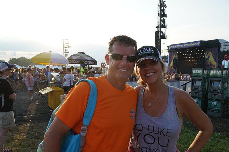 A man and a woman are posing for a picture at a concert.