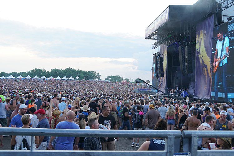 A crowd of people are standing in front of a stage at a concert.