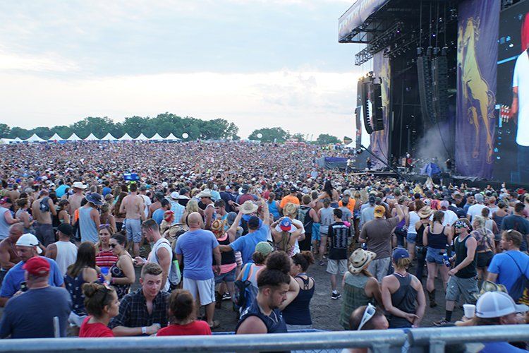 A crowd of people are standing in front of a stage at a concert.