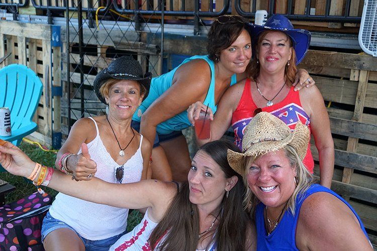 A group of women posing for a picture with one wearing a cowboy hat