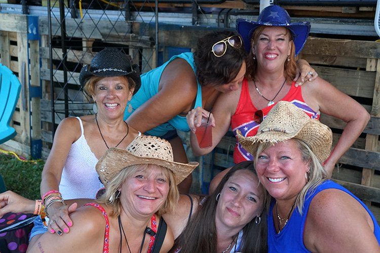 A group of women wearing cowboy hats are posing for a picture.