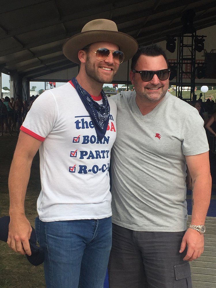 Two men posing for a picture with one wearing a shirt that says born to party rock