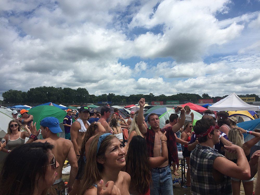 A large group of people are dancing in a field.